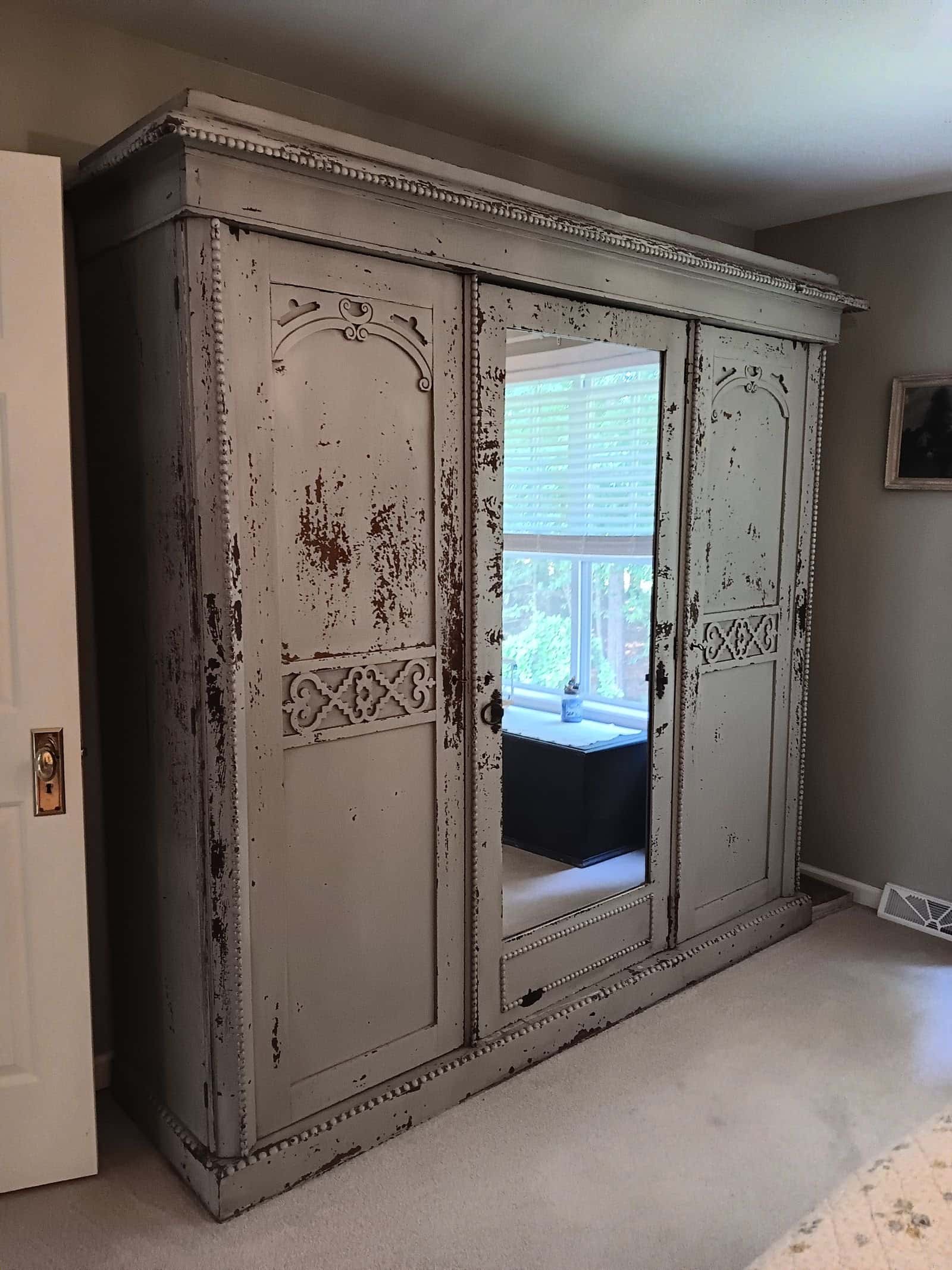 Large antique wood armoire placed in a bedroom after being moved, customer's photo