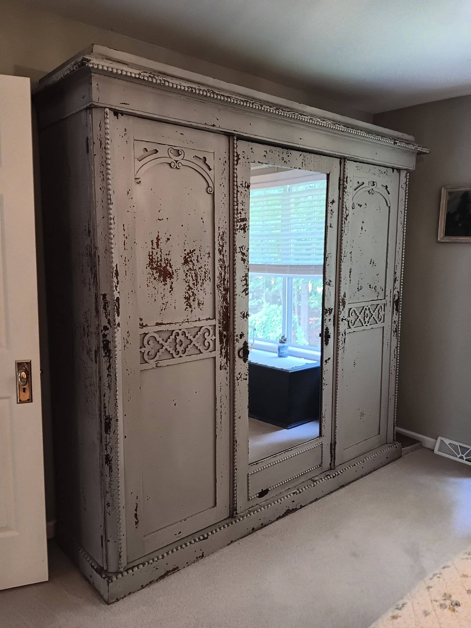 Large antique wood armoire placed in a bedroom after being moved, customer's photo