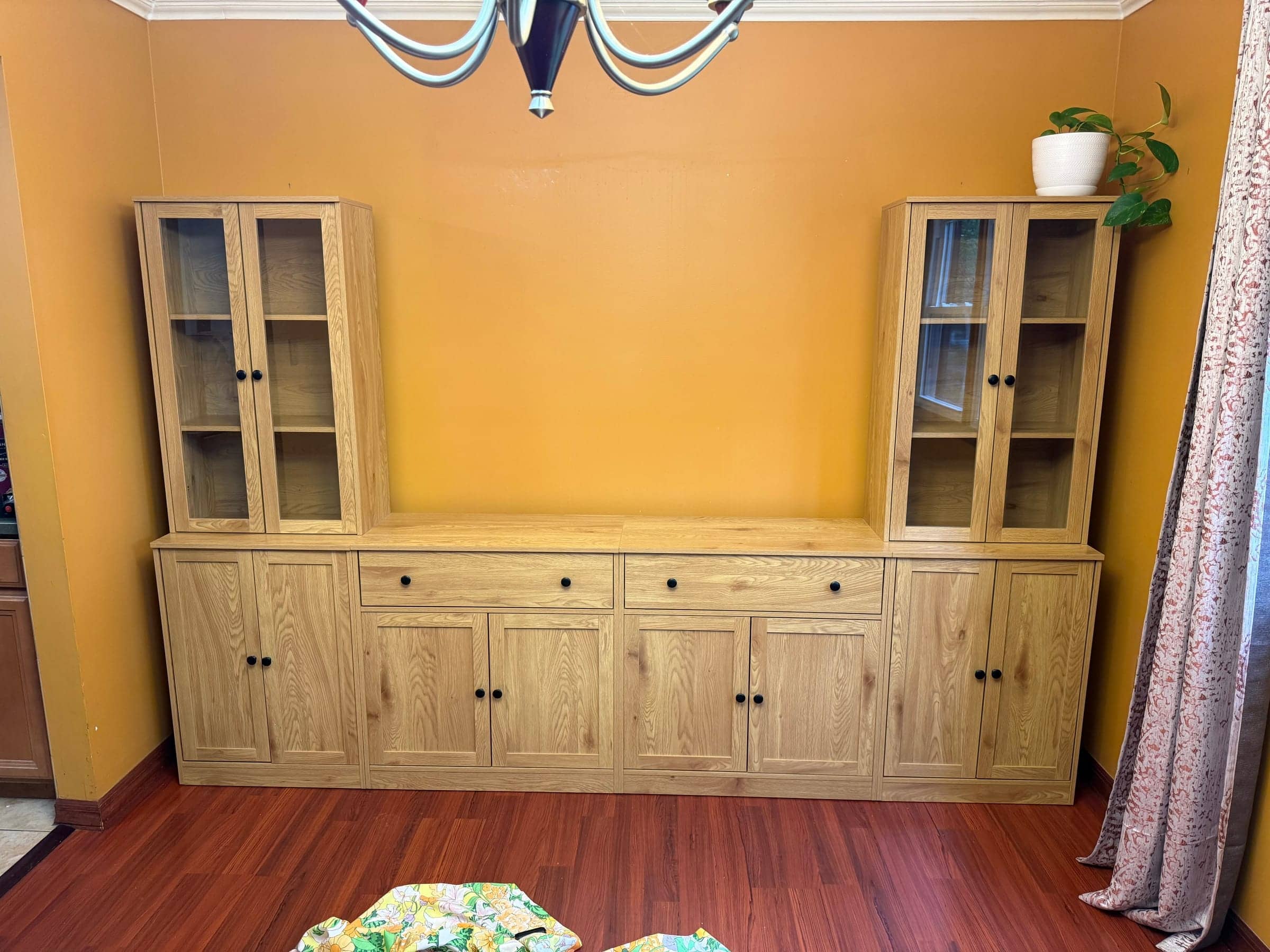 Wood china cabinet and hutch set placed along an orange dining room wall on a red wood floor