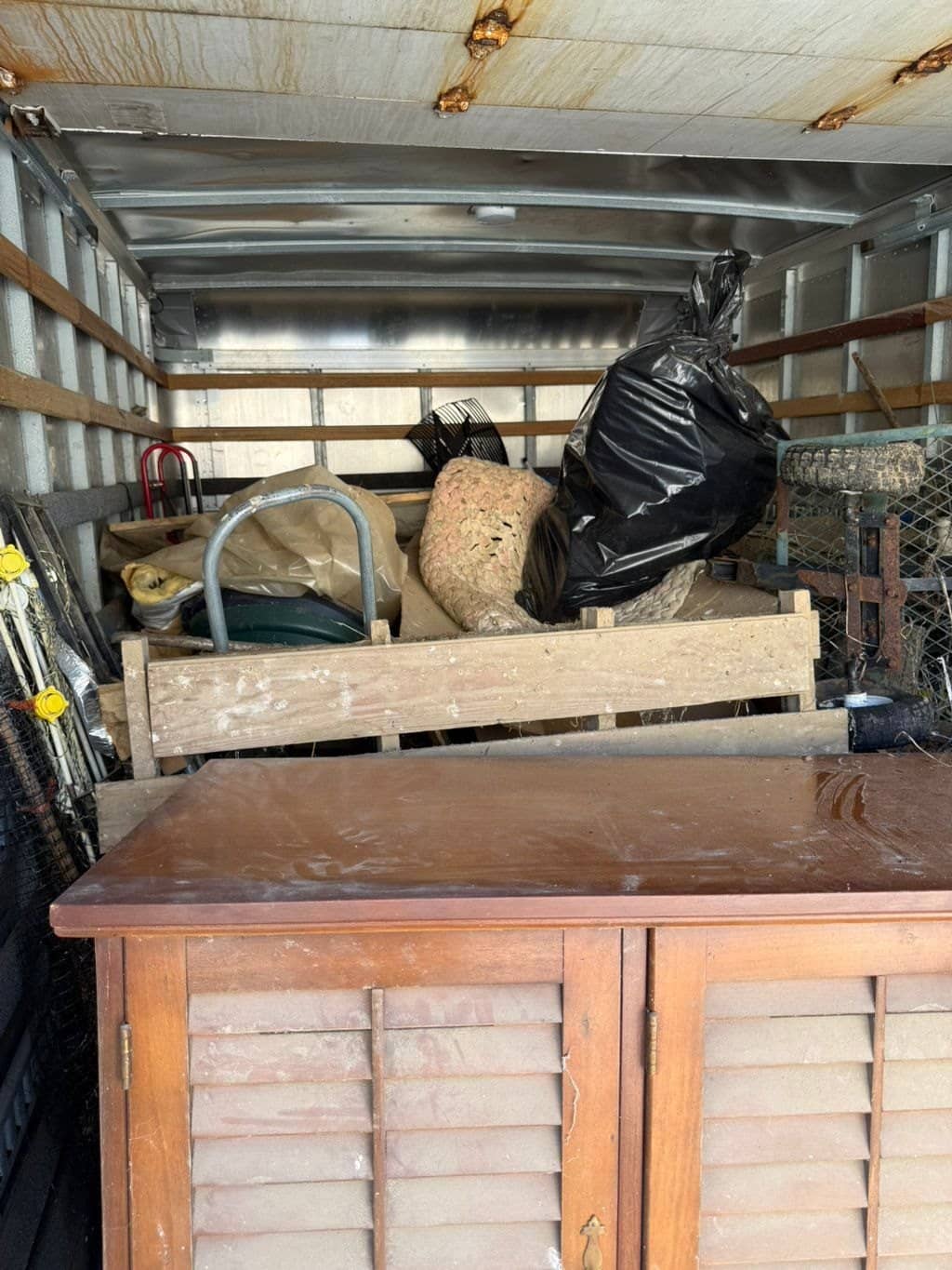 Inside the McWain box truck: a cabinet, baskets, trash bags and household junk loaded for haul-away