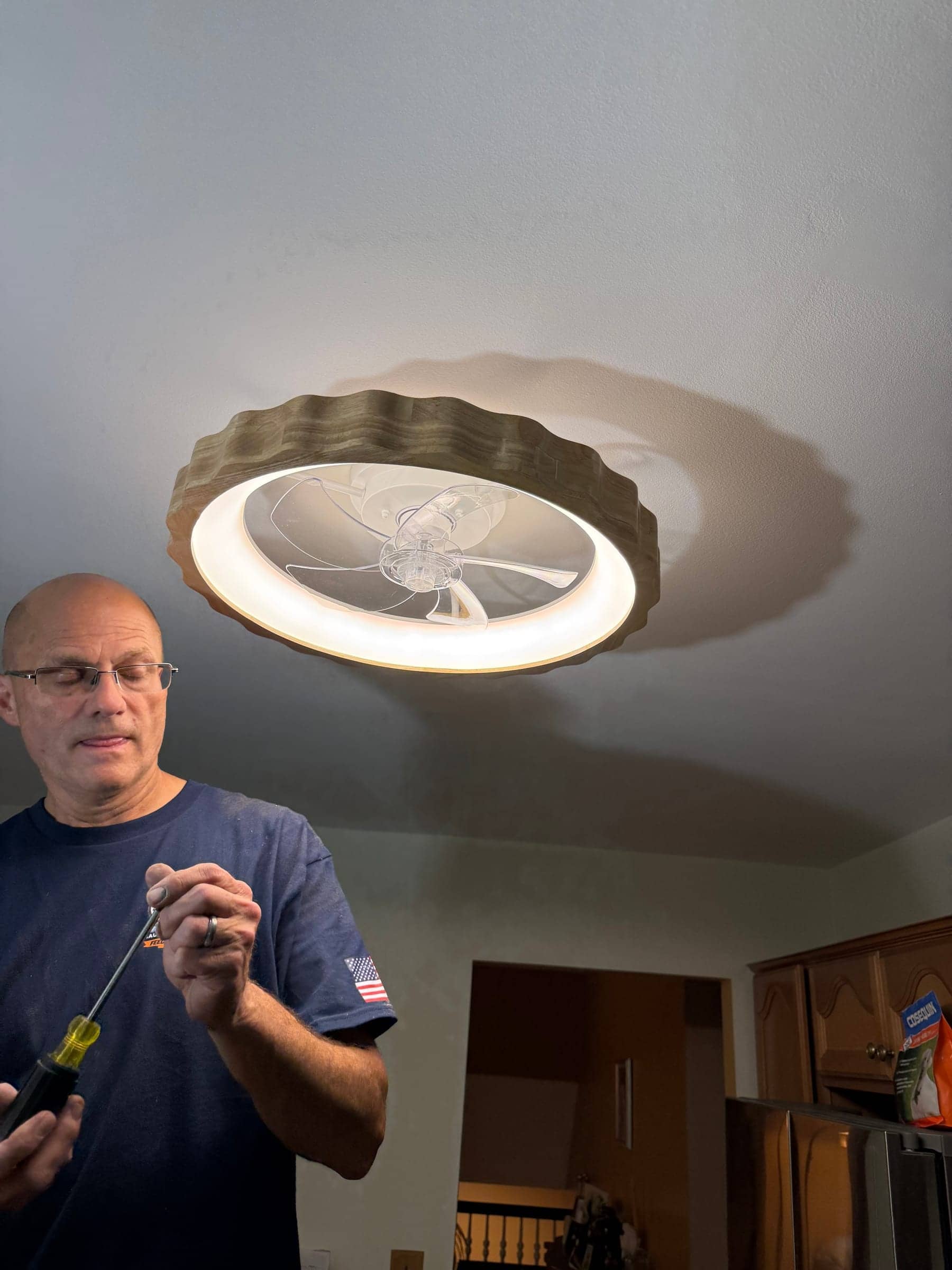 McWain crew member in a navy McWain shirt holding a screwdriver under a newly installed ceiling fan light