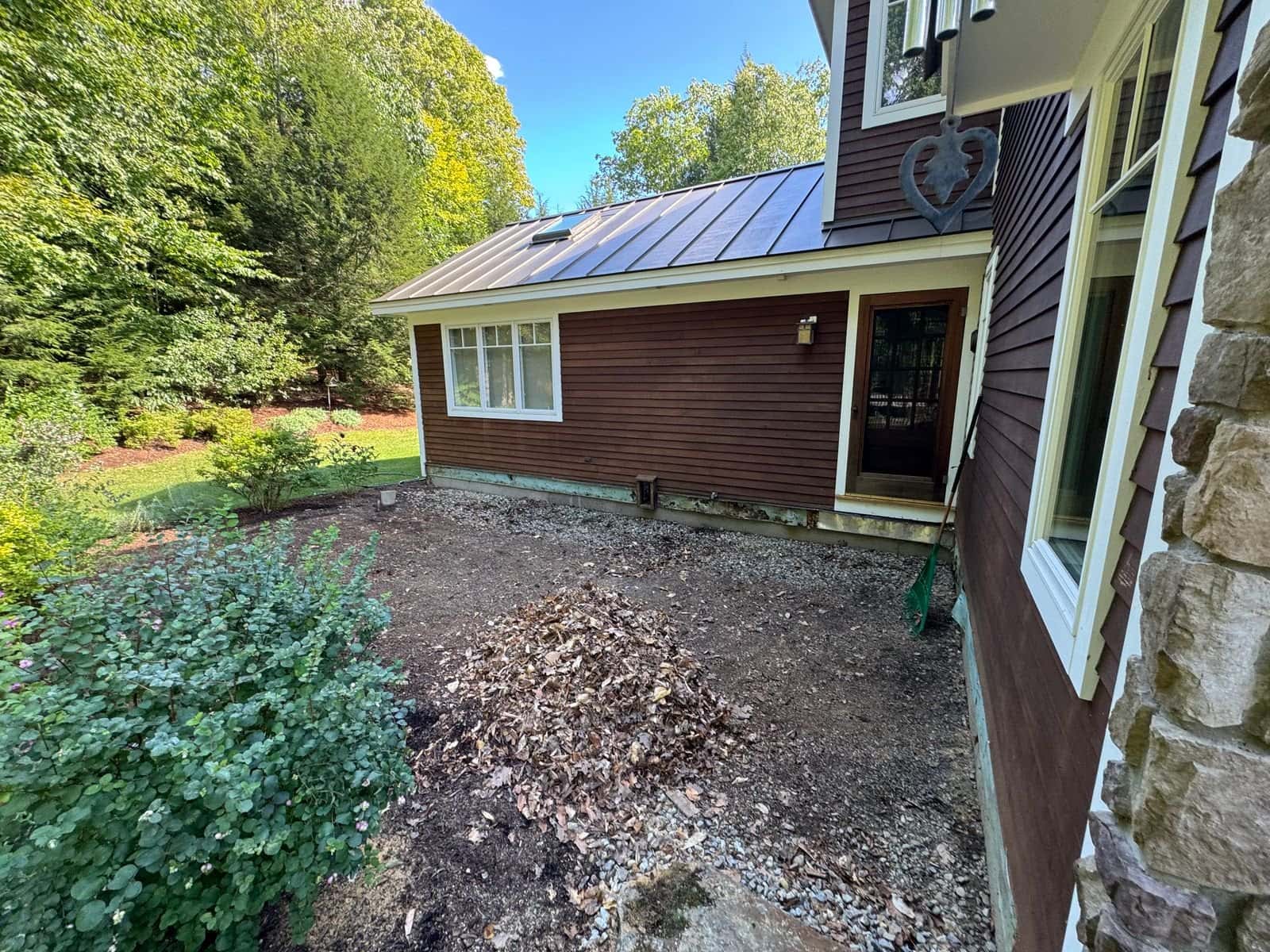 Side yard after deck removal, ground cleared beside the brown-sided house
