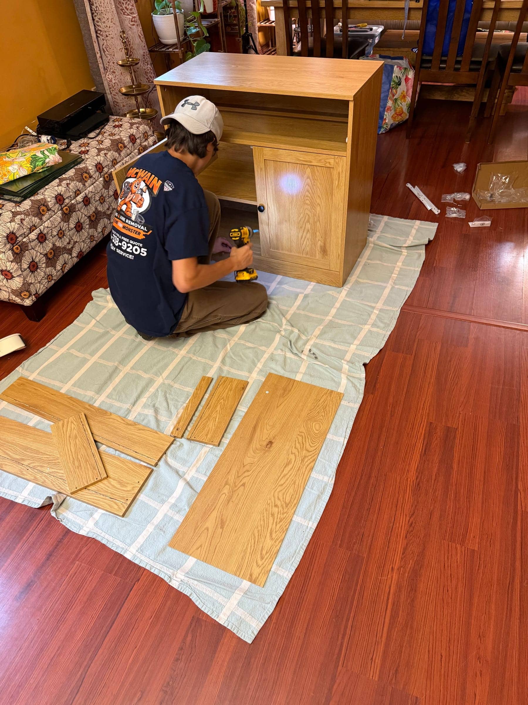 McWain crew member in a McWain shirt assembling a wood cabinet on a drop cloth to protect the floor