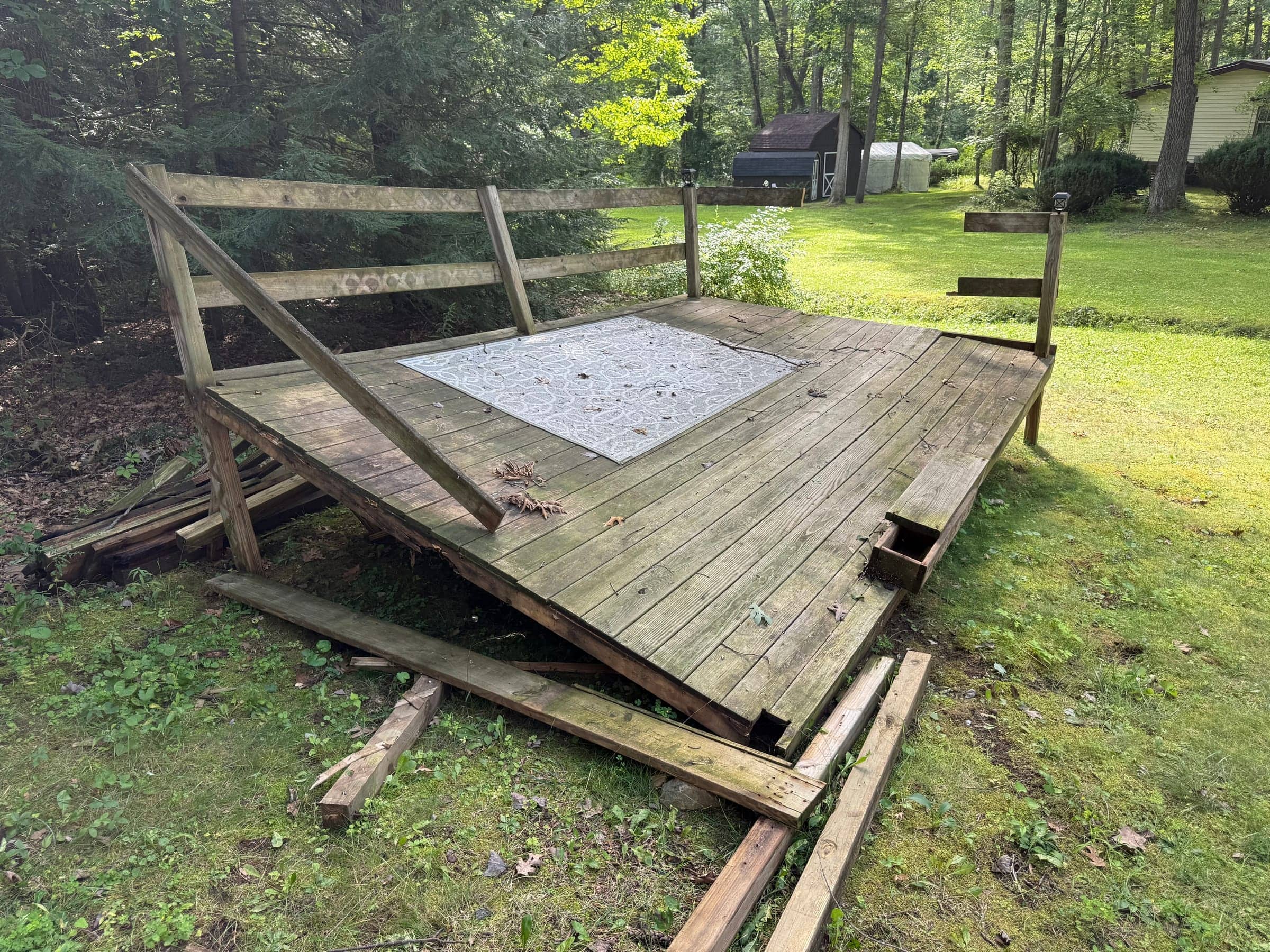 Weathered old wood deck platform sitting in a backyard lawn before removal